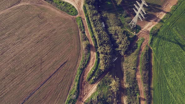 Drone over green fields power lines river bank 4k