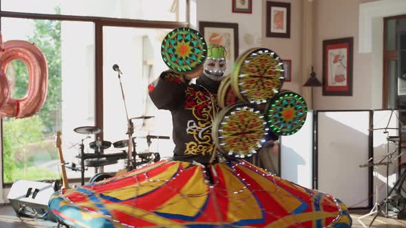 Unrecognizable person dancing national dance tanura indoors. Man in mask show performance at event alt
