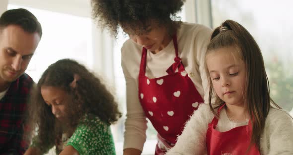Handheld view of children baking cookies with help of parents alt
