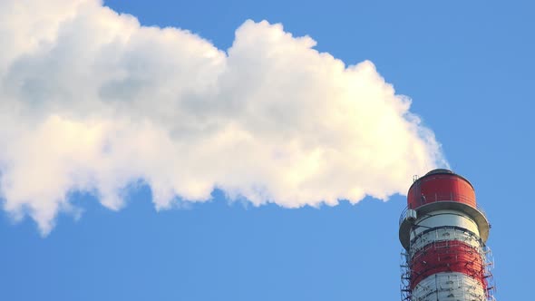 A Smokestack Emits Smoke - the Clear Blue Sky in the Background alt