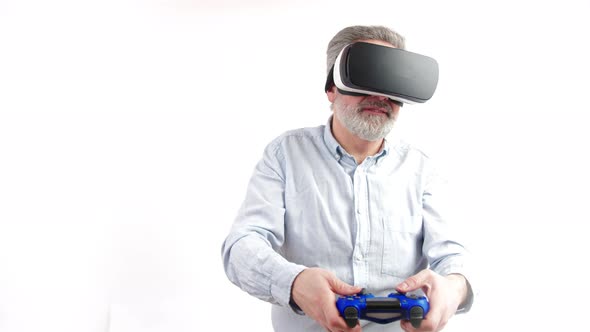 Mature Greyhaired Man Plays Video Games with Vr Goggles and Console Studio Shot Medium Shot White alt