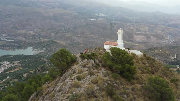 People on a rocky hill with tiny white church in Lecrin Valley, Granada, Spain alt