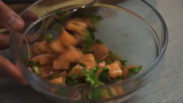 Person stirring healthy bowl with salmon and vegetables.Close up shot. alt