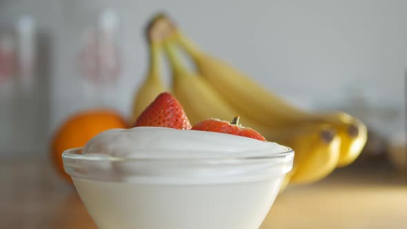 a Man Puts a Few Berries of Ripe Large Strawberries in a Bowl with Whipped Cream alt