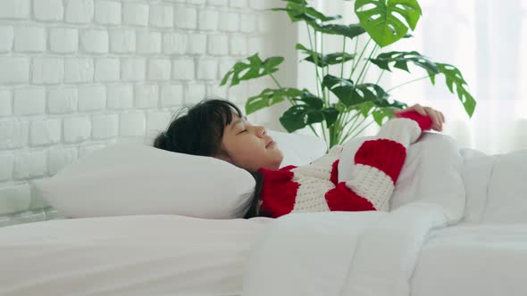 Asian girl kid wearing Pajamas close her eyes smile sleep and sweet dream on bed in bedroom alt