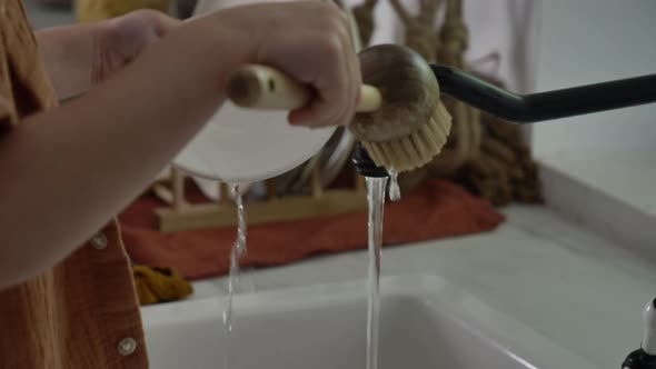 Little boy washing plate in kitchen alt
