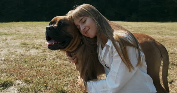 Happy Young Female Cheerfully Playing Sitting with Dog in the Lawn. Love and Friendship alt