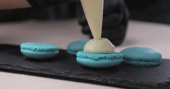 Cooking Food and Baking Concept Chef with Pastry Bag Squeezes Cream Filling Into Macaroon Shells in