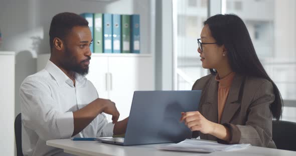 Diverse Business Colleagues Looking at Laptop and Discussing Project in Office alt