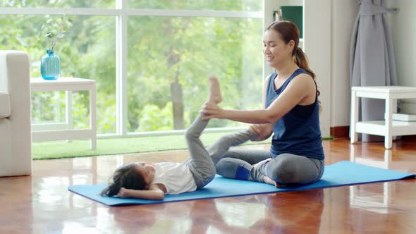 Lovely daughter joyful with her mother to basic yoga exercise 
