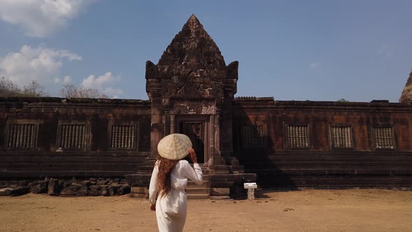 Woman in vietnamese hat go to ancient palace, Wat Phou ruined Hindu Temple. Culture Champasak, Laos alt