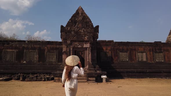 Woman in vietnamese hat go to ancient palace, Wat Phou ruined Hindu Temple. Culture Champasak, Laos