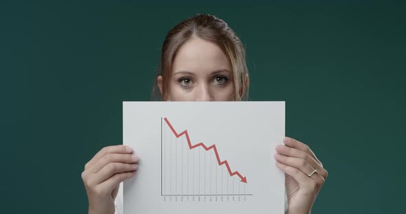 Disappointed businesswoman holding a negative financial chart