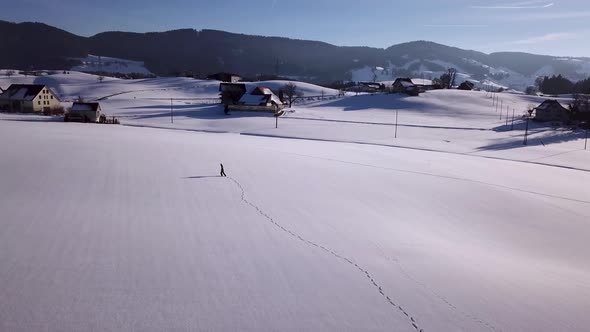 Young man walks in a huge snowy field and stops and looks around in Switzerland while winter. alt