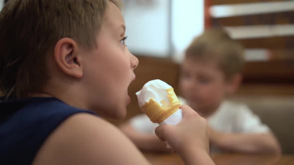 Adorable Little Caucasian Boy Eating Icecream Cone at the Table in Cafe alt