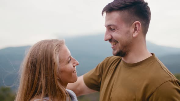 Young Loving Couple Standing and Hugging in Mountains