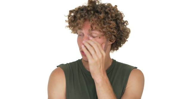 Picture of Guy with Curly Hair Standing Over White Background Feeling Exhausted Tired Touching Face alt