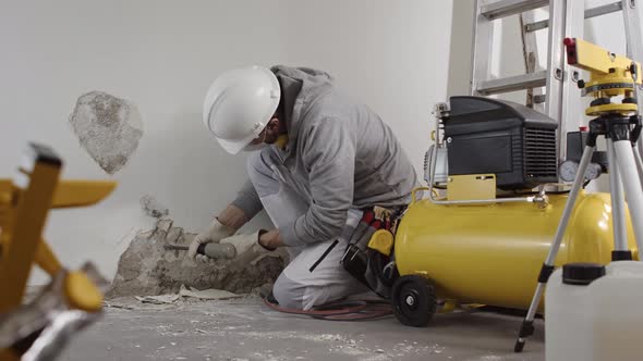 house renovation concept, construction worker wearing helmet at work breaks the old plaster