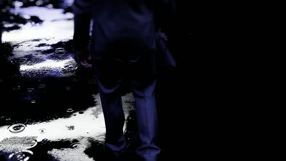 Businessman Walking Alone in the Rain at Night