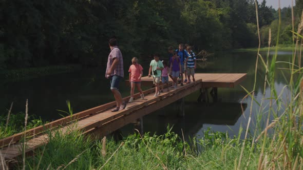 Kids at summer camp follow leader across dock
