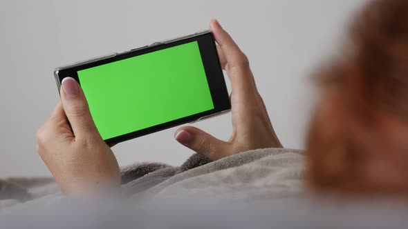 Woman at home with greenscreen smart phone 4K 2160p 30fps UltraHD footage - Female relaxing in bed a alt