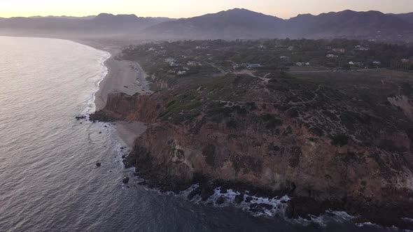 AERIAL: Flight Over Malibu, California View of Beach Shore Line Pacific Ocean at Sunset with alt