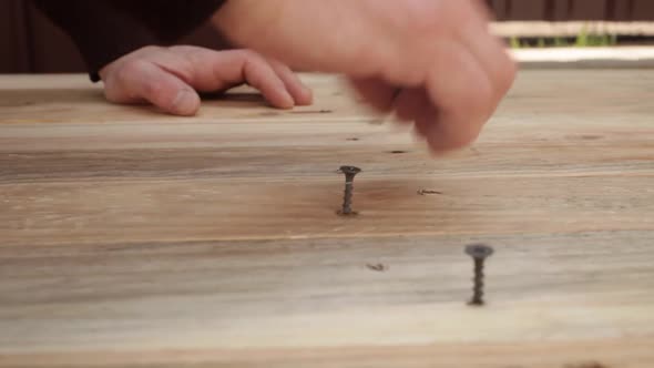 A Man Hammers Nails Into Wooden Boards