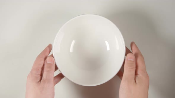 Human Hands Puts A White Soup Bowl On A White Table