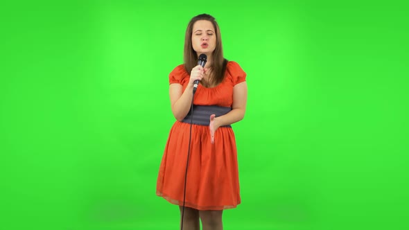 Cute Girl Is Singing Into a Microphone and Moving To the Beat of Music. Green Screen alt