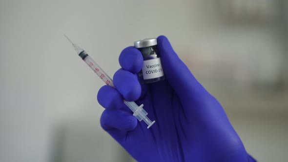 Closeup Hand in Blue Medical Glove with Syringe and Covid19 Vaccine Jab alt