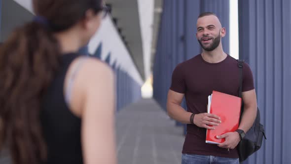 Man Holding Books and Talking with Friend in University Campus