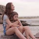Two Cute Sisters Sitting at the Beach of the Sea - VideoHive Item for Sale