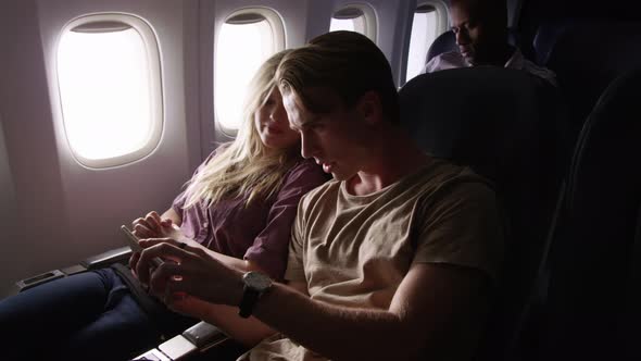 Couple taking selfies with mobile phone on airplane