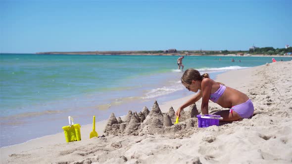 Little Girl at Tropical White Beach Making Sand Castle