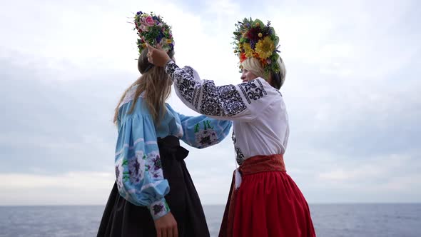 Two Confident Young Ukrainian Women Touching Head Wreathes in Slow Motion Turning Looking at Camera alt
