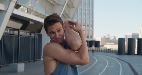 Athletic Man Warming and Stretching His Arms to Ready for Training Outdoors on Stadium alt