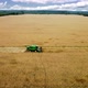 Drone flying over combine harvester working on wheat field in a sunny bright day - VideoHive Item for Sale