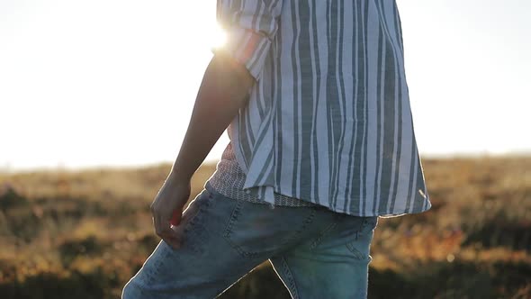 Male in Jeans and Shirt Walks Through the Field