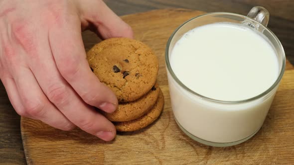 Hand putting a cookie beside glass of milk. Close up. 4k