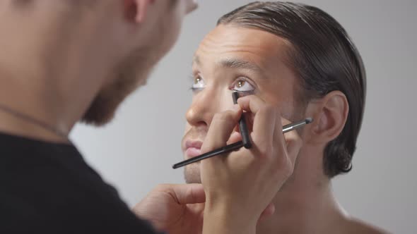 Male MUA Applying Black Eyeliner on Handsome Man alt