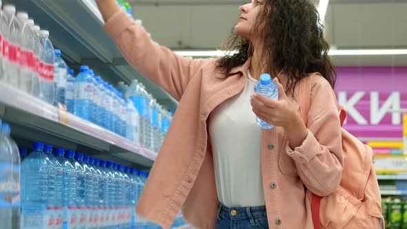 Woman is Buying Bottled Water in Supermarket alt