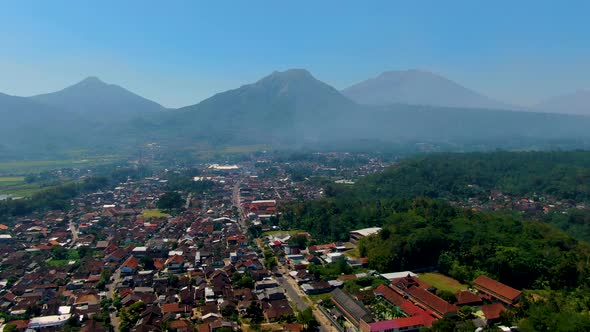 Grabag village in valley below majestic Java volcanoes silhouettes aerial view alt