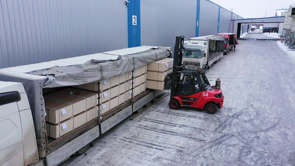 A Loader is Loading Chipboard Packages Into the Truck at the Factory