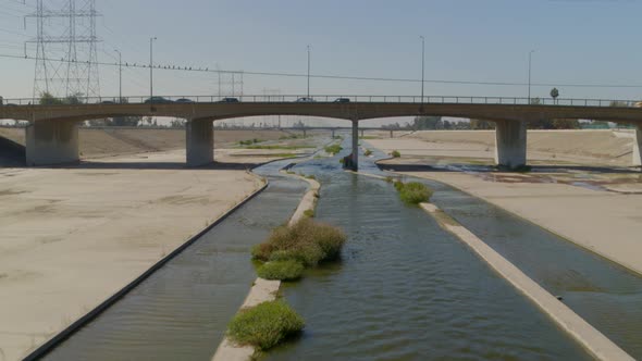 Vehicles riding on bridge and Los Angeles canal in city, United States alt