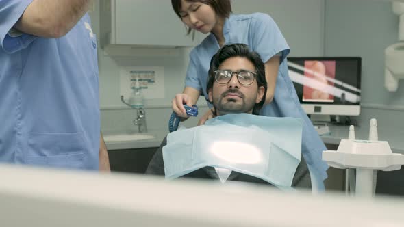 Dentist and dental assistant preparing dental treatment for patient alt