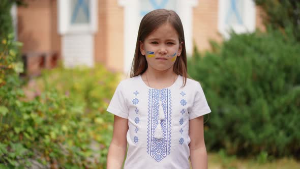 Sad Girl in Traditional Clothing Looking at Camera with Serious Facial Expression Showing Help alt