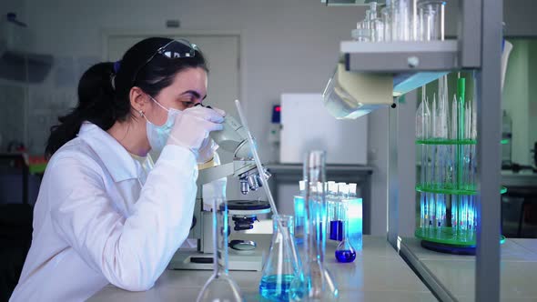 Female Microbiologist Looking Into Microscope in Medical Science Laboratory alt