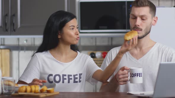 Loving Wife Feeding Husband with Croissant on Breakfast alt