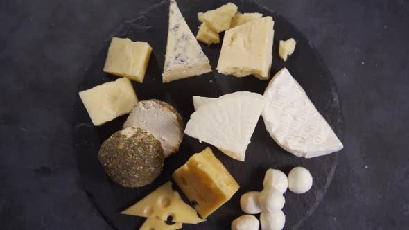 Various Types of Cheese on Dark Cutting Board Top View