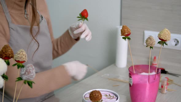 A Girl in White Gloves Cuts Off the Excess with Strawberries on a Stick